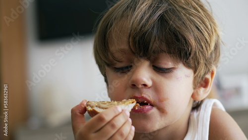 Portrait of a young boy snacking peanut butter bread. Closeup child face eating snack food toast
