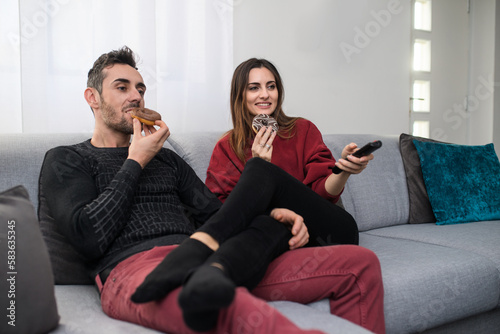 Happy couple eating donuts at home