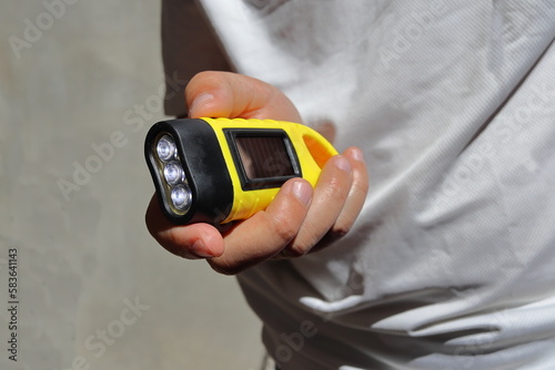 A man holds in his hands a hand-crank solar torch, for travel and hiking