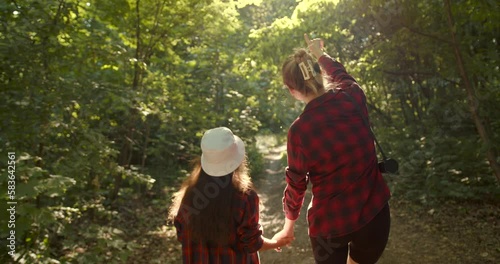 Mother and daughter hiking together in green forest