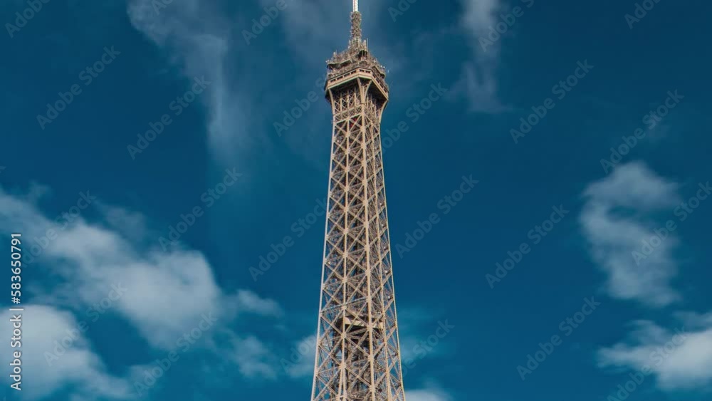 Top of the Eiffel tower timelapse from waterfront at the river Seine in Paris. Viewpoint with tourists on observation deck at sunny summer day. Zooming out