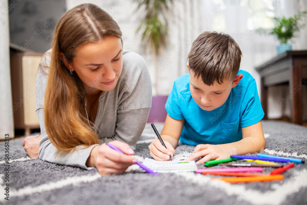 Happy family playing together on floor. Mother and son painting together Happy family playing together on floor. Mother and son painting together