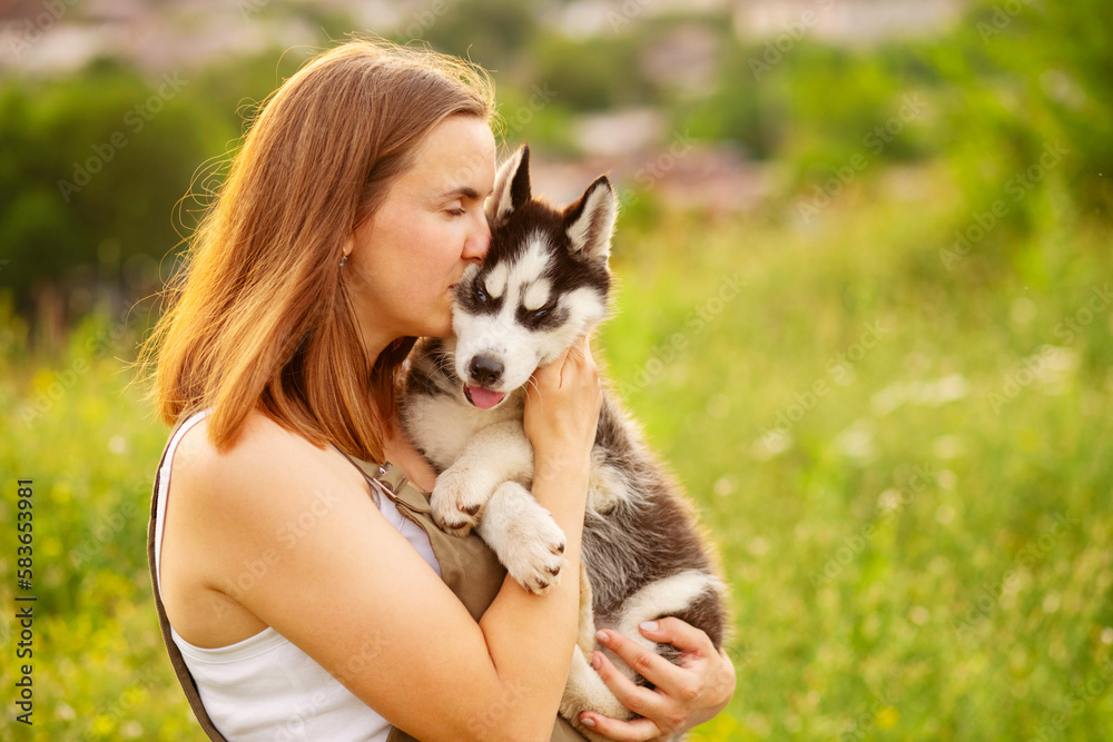 Woman playing with cute little husky puppy dog outdoors. Pet and owner love Woman playing with cute little husky puppy dog outdoors. Pet and owner love