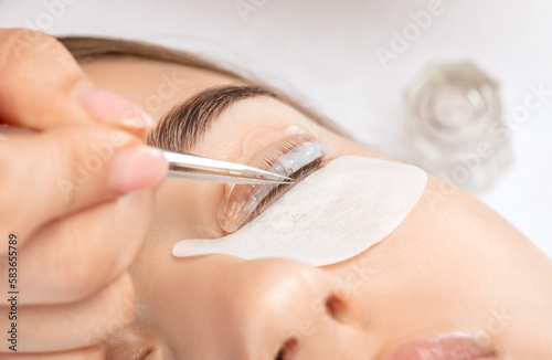 Make-up artist makes the procedure of lamination and dyeing of eyelashes to a beautiful woman in a beauty salon. Eyelash extensions. Eyelash lifting