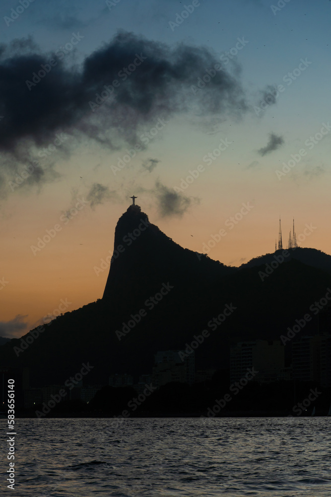 Sunset in the bay of Guanabara, cove and beaches of Rio de Janeiro, Brazil with its buildings, boats and landscape. Christ the Redeemer on top of Corcovado. Reflection of the sky in the sea