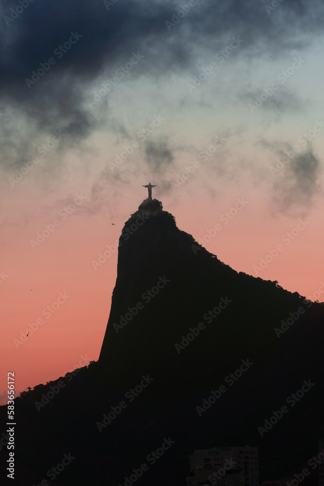 Sunset in the bay of Guanabara, inlet and beaches of Rio de Janeiro, Brazil with its buildings, boats and landscape. Christ the Redeemer on top of Corcovado. Reflection of the sky in the sea. Twilight