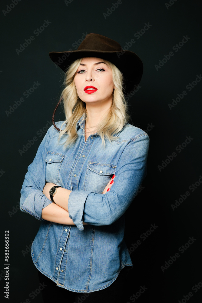 Blonde cowgirl wearing denim blue shirt with a cowboy hat. 