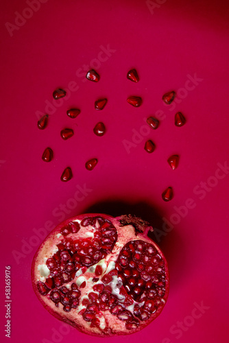 Half pomegranate and pomegranate seeds on red background 