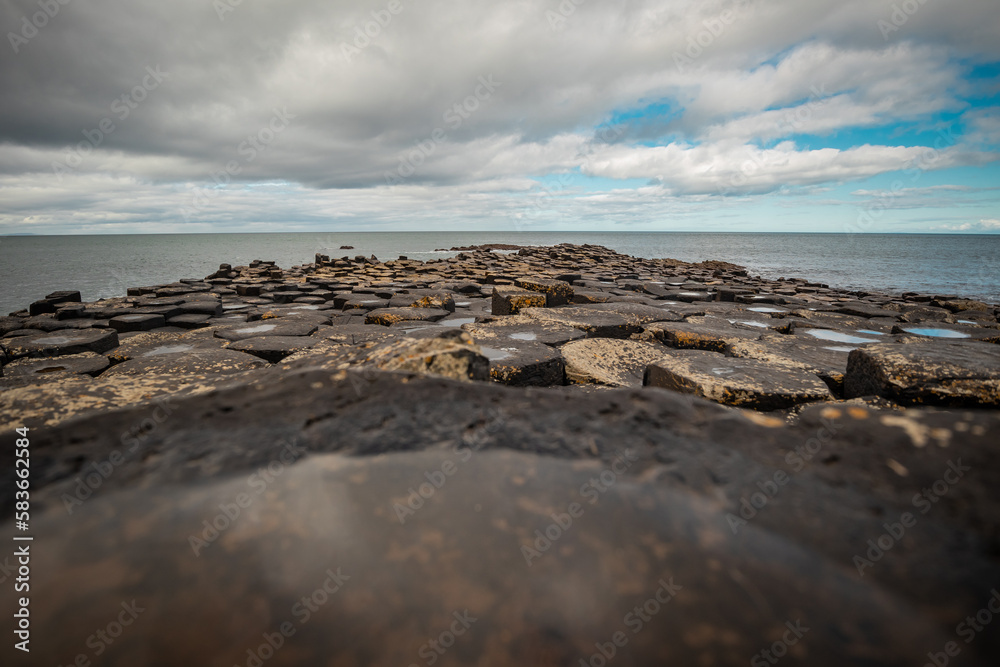 Panorama of hexagonal stones or pillars at Giants causeway in northern ireland, majestic basalt pillars at the beach on a cloudy day. Wide view of area..