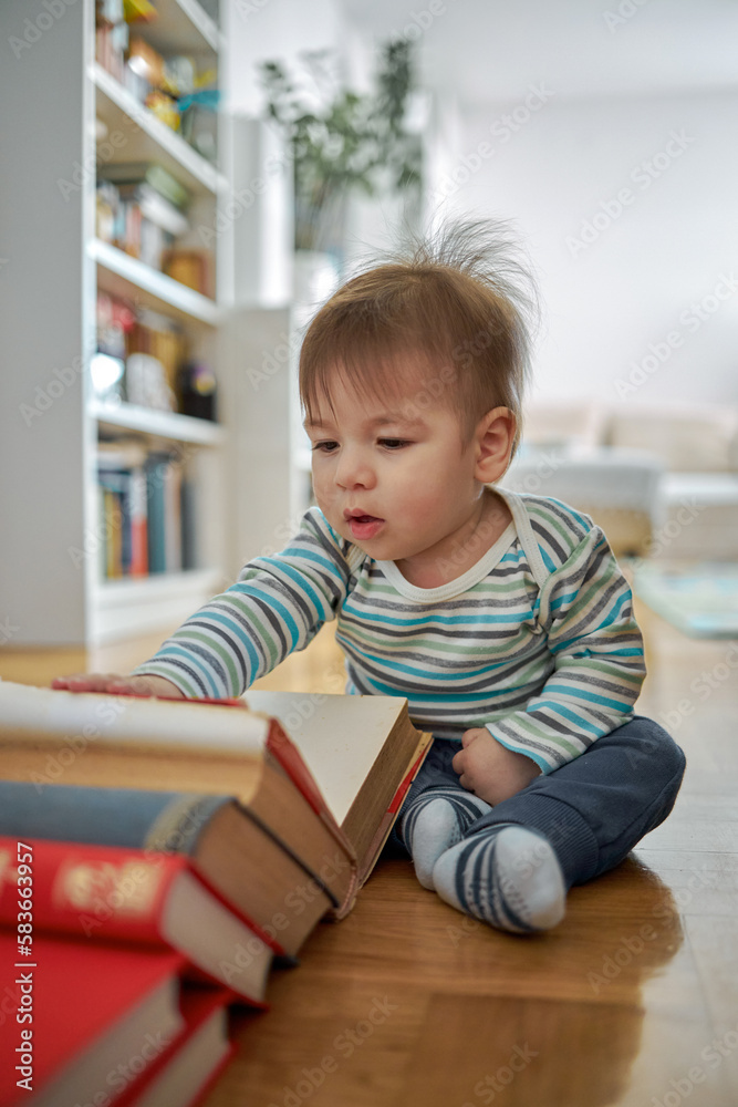Cute baby sitting and looking at a large book.