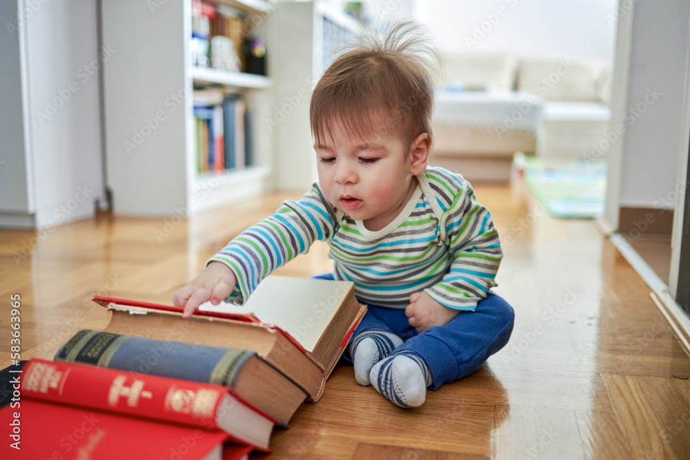 Cute baby sitting and looking at a large book.