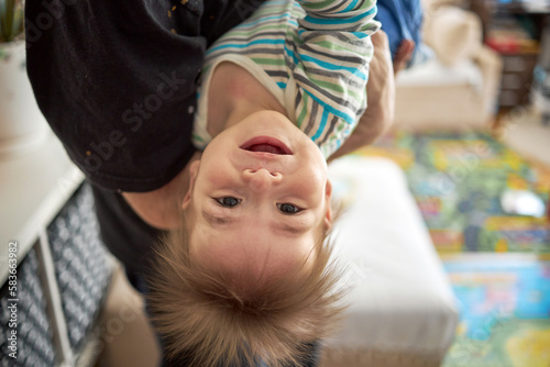 Obraz na płótnie Little boy cute child baby playing with his father, hanging upside down. Toddler having fun at home. Happy childhood, family love concept w salonie