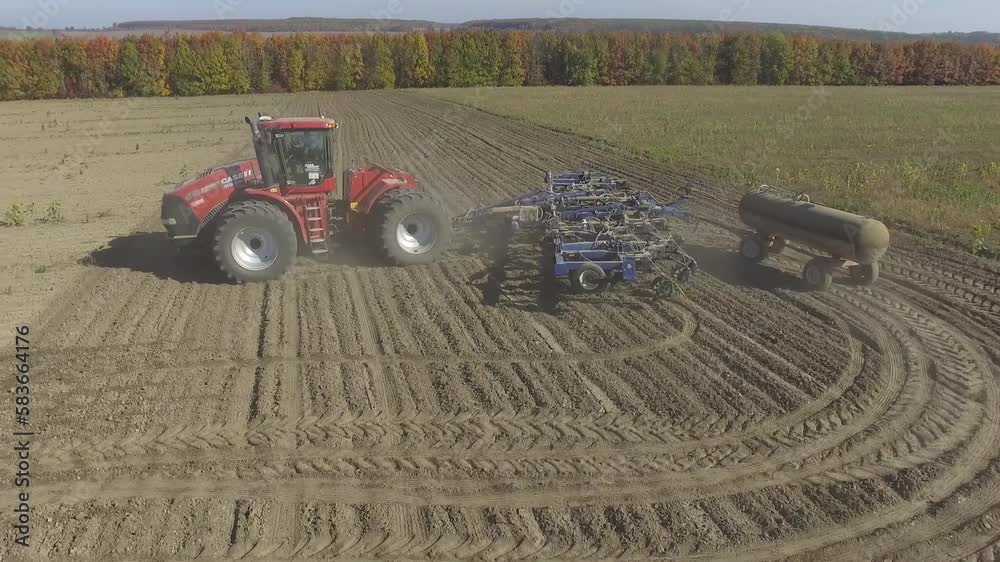 Big red tractor working on the field cultivating and applying nitrogen ASP