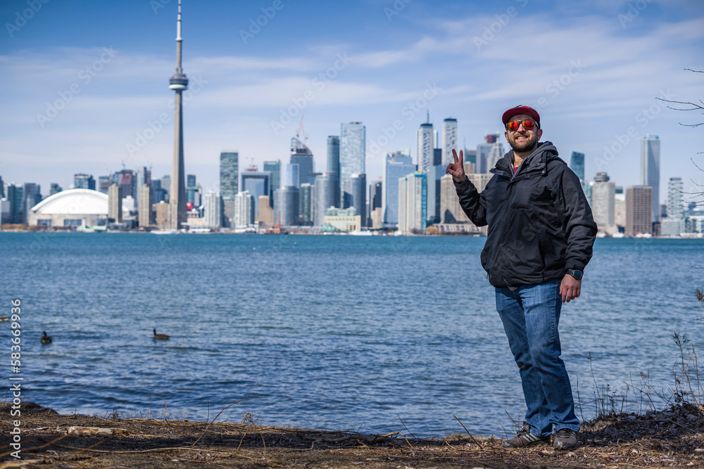 man poses on the coast of toronto island park with toronto skyline on background