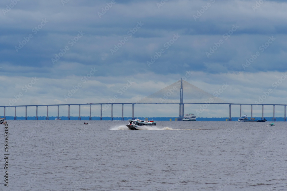 Amazon river with Manaus bridge with some boats and a large cruise ship. Location: Manaus, Brazil