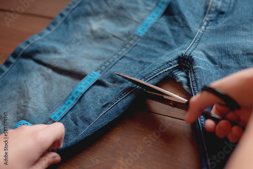 Denim Upcycling Ideas, Using Old Jeans, Repurposing Jeans, Reusing Old Jeans, Upcycle Stuff. Woman seamstress cut and repair old blue jeans.