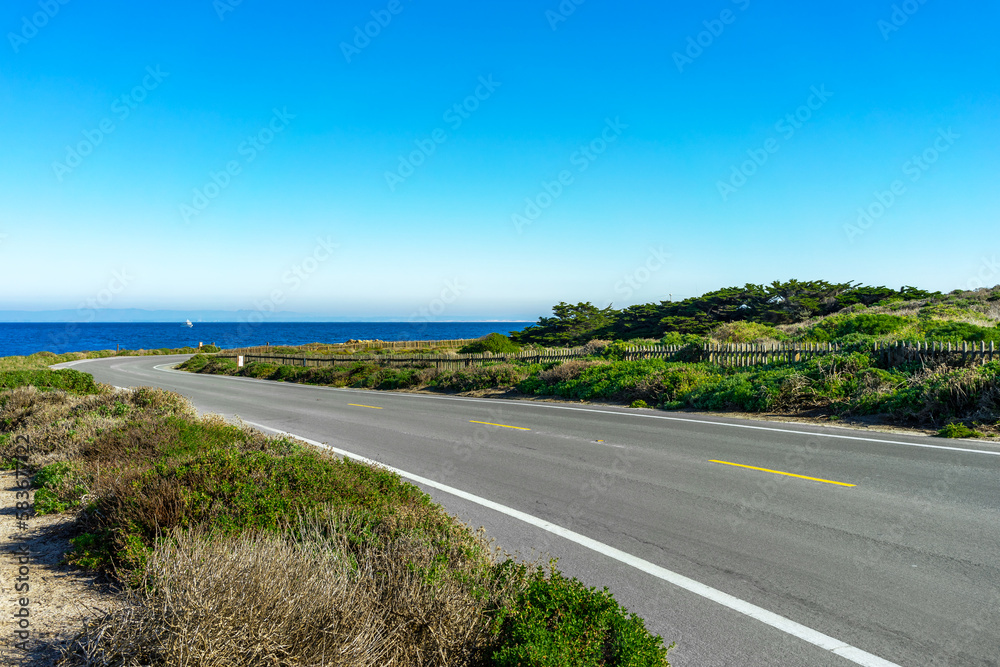 A empty rural road withe green landscape next to the Pacific Ocean
