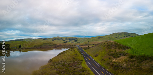 Empty road by green hills and reservoir in beautiful California at dawn photo