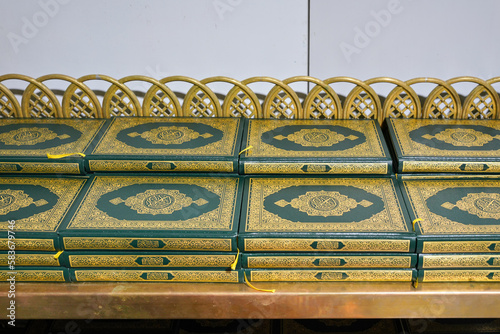 Stacks of green and golden Quran or Quraan books at shelf, closeup detail photo