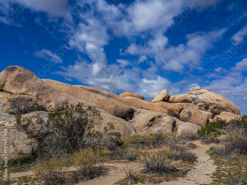 Huge, smooth boulder pile in Joshua Tree National Park's desert area on a bright blue sky day.