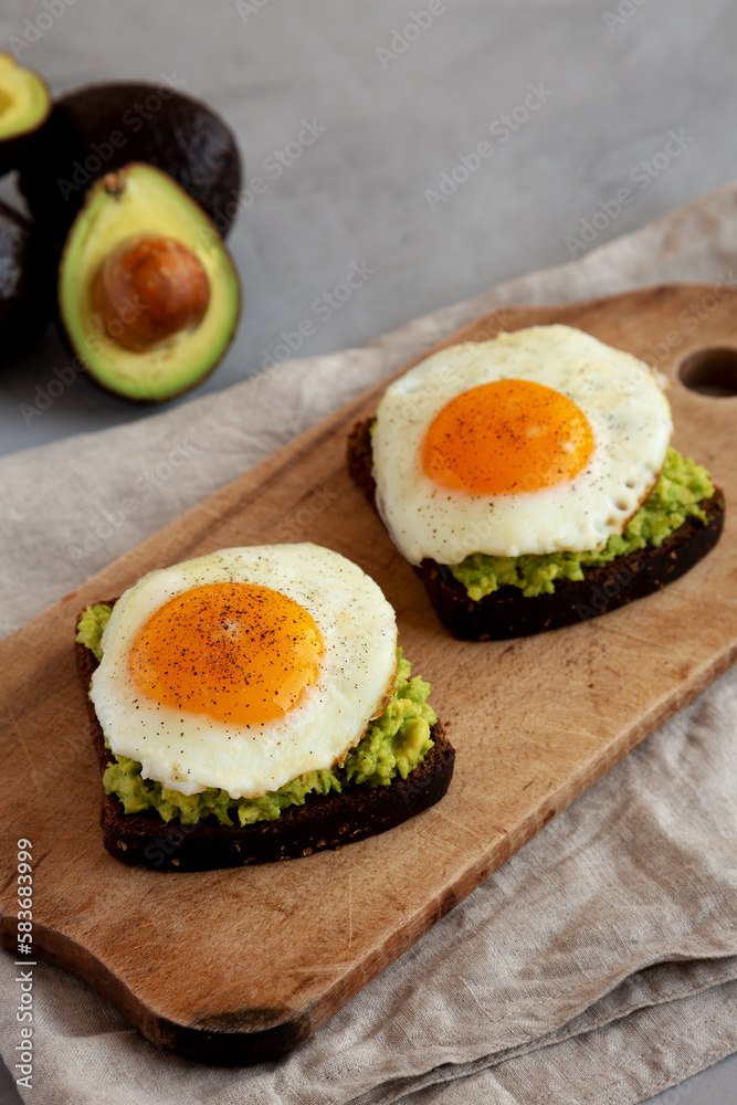 Homemade Avocado Toast with Eggs on a rustic wooden board, side view. Homemade Avocado Toast with Eggs on a rustic wooden board, side view.