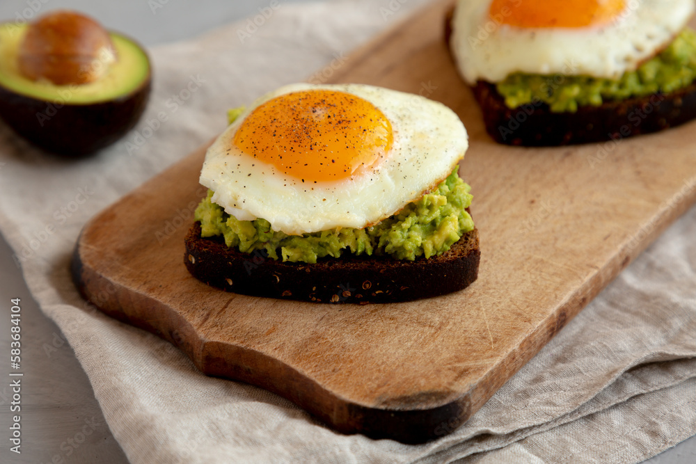 Homemade Avocado Toast with Eggs on a rustic wooden board, side view. Homemade Avocado Toast with Eggs on a rustic wooden board, side view.
