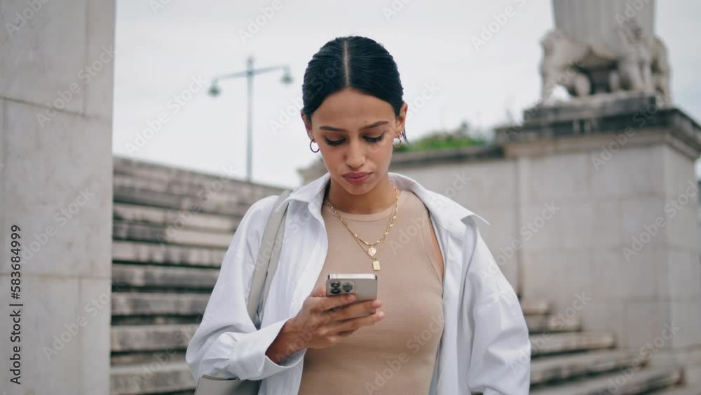Angry girl holding smartphone waiting at street. Nervous woman looking distance Angry girl holding smartphone waiting at street. Nervous woman looking distance