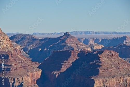 Bright desert sunlight shines down on the Grand Canyon  casting shadows on every crease and layer of the eroded canyon carved over many years by the Colorado River thousands of feet below