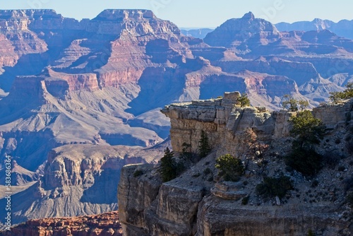 Bright desert sunlight shines down on the Grand Canyon, casting shadows on every crease and layer of the eroded canyon carved over many years by the Colorado River thousands of feet below