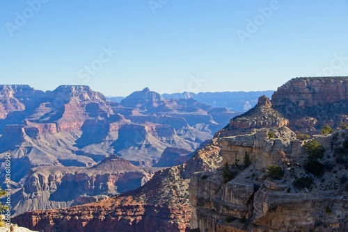 Bright desert sunlight shines down on the Grand Canyon, casting shadows on every crease and layer of the eroded canyon carved over many years by the Colorado River thousands of feet below