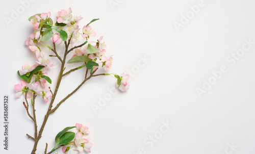 A branch with textile cherry blossoms on a white background, top view, home decor