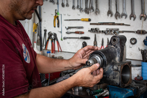 Mecánico reparando un repuesto de automovil en su taller