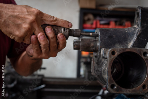 Mecánico ajustando pieza de automovil en su taller