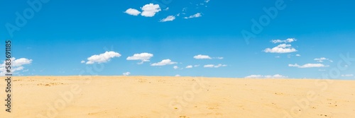 Sand dunes and blue sky with white clouds, natural background.