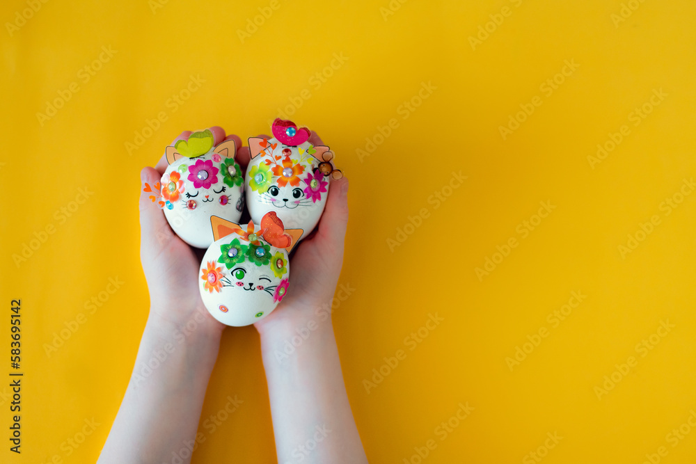 Three Easter eggs in the hands of a child on the yellow background. Easter concept. Three Easter eggs in the hands of a child on the yellow background. Easter concept.