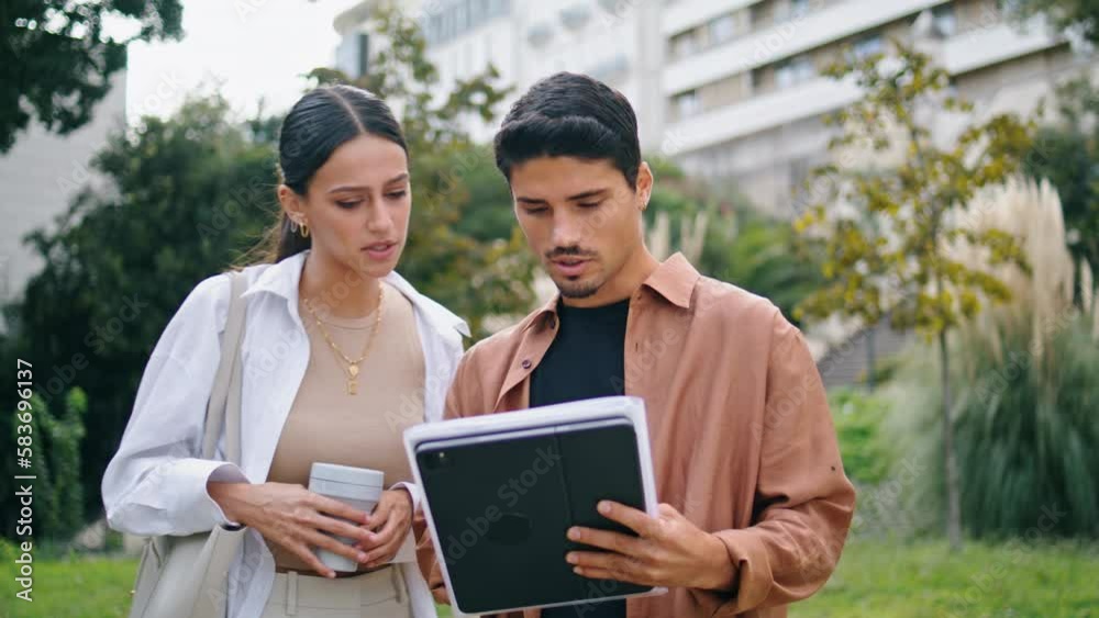 Focused colleagues reading papers outdoors. Business partners working walking Focused colleagues reading papers outdoors. Business partners working walking