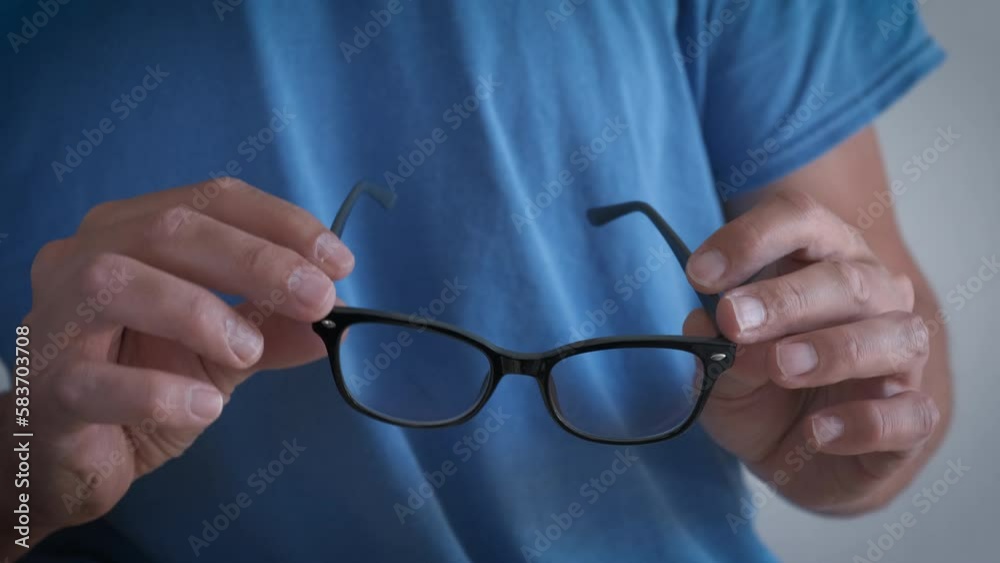 Man hold glasses with black frame. A view of man hands holding a modern glasses with black frame in the room. Man hold glasses with black frame. A view of man hands holding a modern glasses with black frame in the room.
