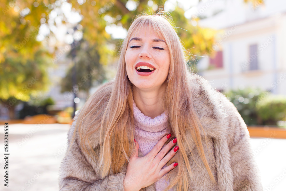young pretty woman laughing out loud at some hilarious joke, feeling happy and cheerful, having fun