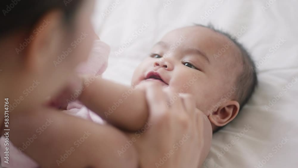 Close up portrait of beautiful young asian mother and her newborn baby in a bed.Mother hands holding newborn baby feet.Concept of mom day,love,parenthood,asian family. Close up portrait of beautiful young asian mother and her newborn baby in a bed.Mother hands holding newborn baby feet.Concept of mom day,love,parenthood,asian family.