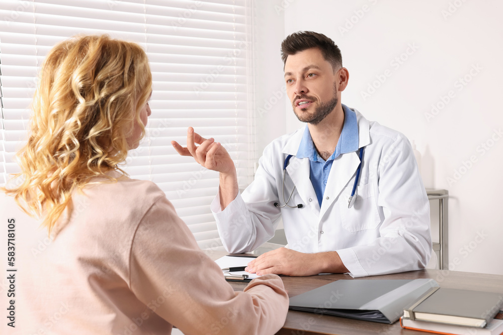 Doctor consulting patient at table in clinic Doctor consulting patient at table in clinic