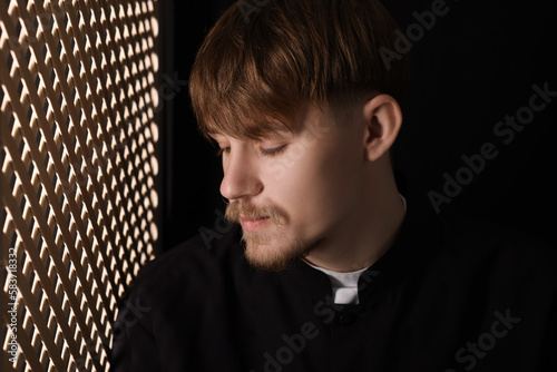 Foto Catholic priest near wooden window in confessional booth