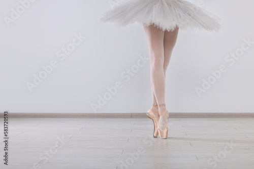 Young ballerina in pointe shoes practicing dance moves at studio, closeup. Space for text