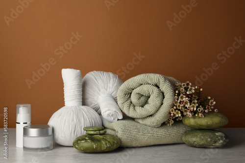 Composition with different spa products and flowers on beige table against brown background