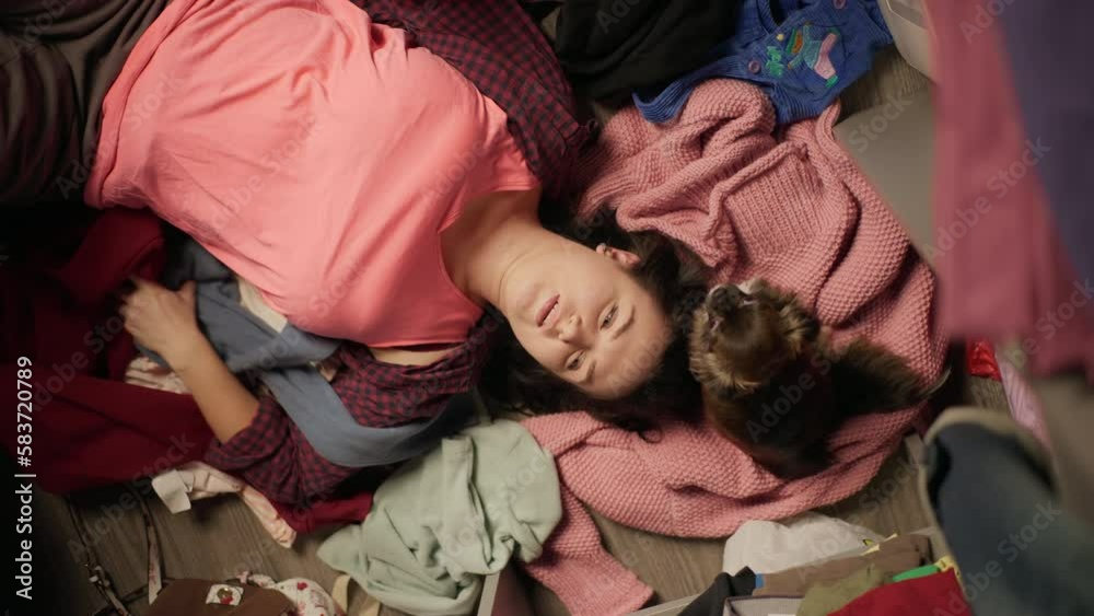 A girl with a dog in a wardrobe with clothes. A woman chooses T-shirts and throws them away. overcoming depression. High quality 4k footage