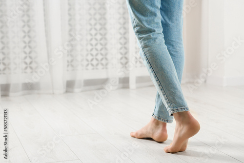 Woman stepping barefoot in room at home, closeup with space for text. Floor heating