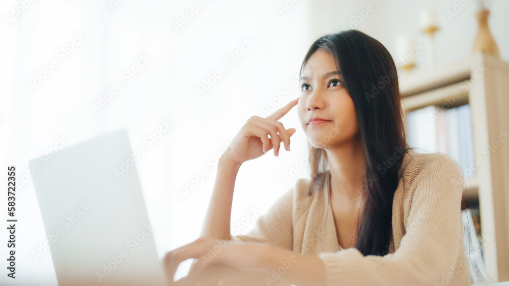 Young asian woman working on computer laptop on desk in living room at home Young asian woman working on computer laptop on desk in living room at home