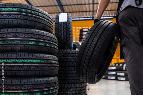 Close-up of New tires, A male auto mechanic storing or stocking new tires at a large warehouse at a service center or auto repair shop for the automotive industry. automobile industry.