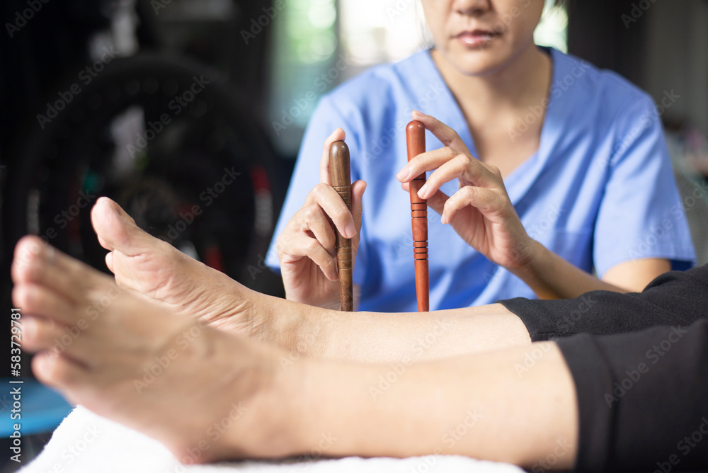 Hands physiotherapist massaging with wood stick on feet,Reflexology spot thai foot massage
