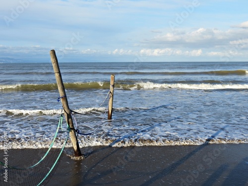 Postes de madera y red caída engullidos por el mar en una playa