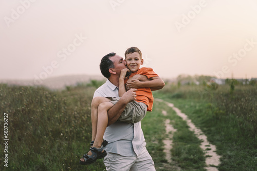 Happy Fathers day. Father with son are walking in the field. Dad hugs boy. The concept of Fathers day, relationships with children, care and love. © Анастасія Стягайло